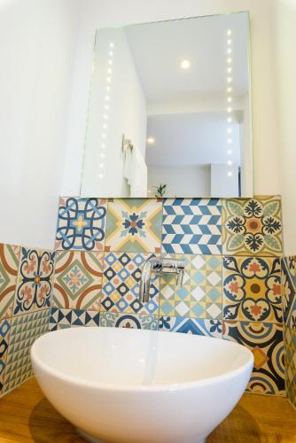 La salle de bains est pourvue d'un lavabo, d'un miroir et de carrelage. dans l'établissement L' échafaud - Apparts de standing - Centre historique, à Périgueux