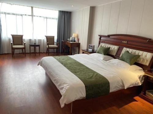 GreenTree Alliance Hotel Jiangsu Suzhou Xiangcheng Distrcit Dongqiao في Sangshubang: غرفة نوم بسرير كبير وطاولة وكراسي