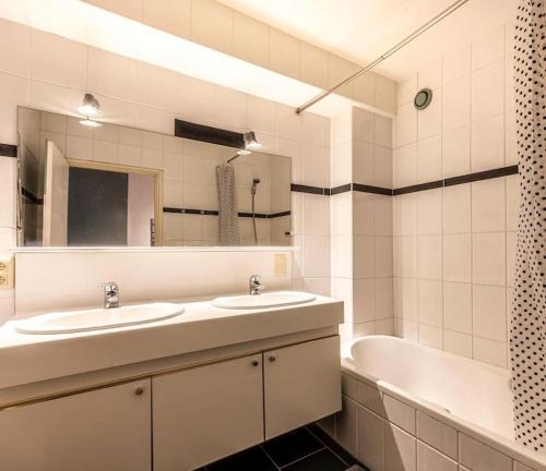 ein Badezimmer mit zwei Waschbecken, einer Badewanne und einem Spiegel in der Unterkunft Appartement Knokke-Heist in Knokke-Heist
