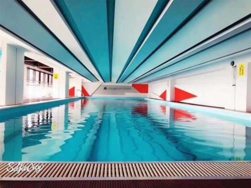 a large swimming pool with blue water in a building at GreenTree Inn Express Kunming East Passenger Station Huazhicheng in Kunming