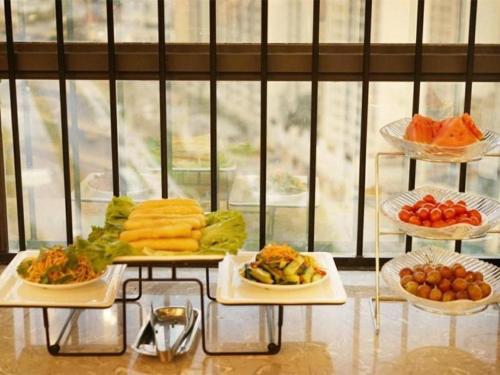 a buffet with several plates of food on a table at GreenTree Inn Express Kunming East Passenger Station Huazhicheng in Kunming