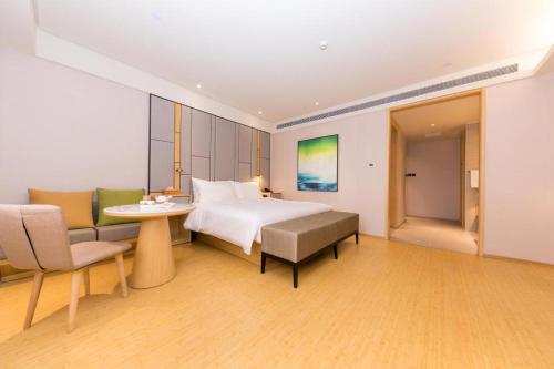 Ji Hotel Jinan 2nd Ring Xi Road في Luokou: غرفة فندقية بسرير وطاولة وكراسي