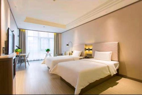 ein Hotelzimmer mit 2 Betten und einem TV in der Unterkunft Hanting Hotel Xian Changqing Road Metro Station in Xi'an
