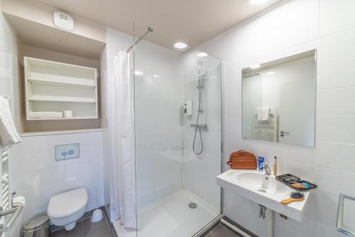 La salle de bains blanche est pourvue d'une douche et d'un lavabo. dans l'établissement Break and Home Campus Condorcet Maison des chercheurs, à Aubervilliers