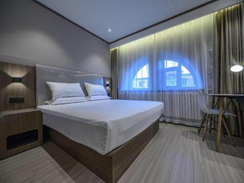 Un dormitorio con una cama grande y una ventana en Hanting Hotel Changchun Chongqing Road Vivid City en Changchún