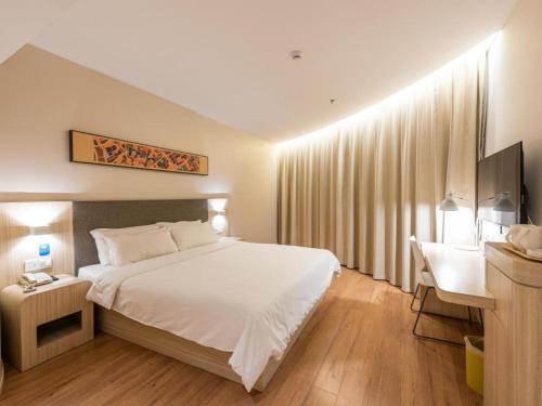 Un pat sau paturi într-o cameră la Hanting Hotel Jinan Guo Branch