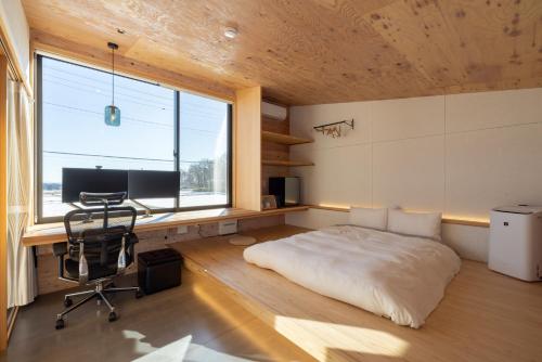 a bedroom with a bed and a desk and a computer at 森deワーケなすっぽ 木の温もりとホテルライクな佇まい 森のバレルサウナ in Nasu