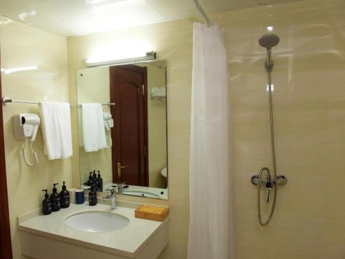 ein Bad mit einem Waschbecken und einer Dusche mit einem Spiegel in der Unterkunft Starway Hotel Ha'Erbin Convention And Exhibition Center in Harbin