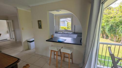 a kitchen with a counter with stools and a window at Rainforest Deluxe Bungalow in Port Macquarie