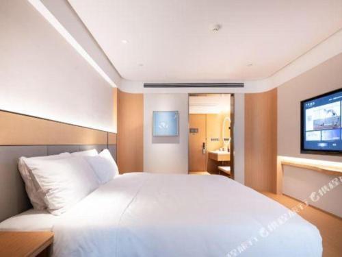 a bedroom with a large white bed and a flat screen tv at Ji Hotel Jiaxing Shanshan Impression Plaza in Jiaxing