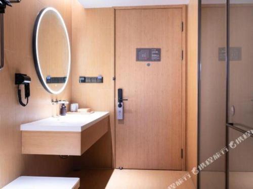 a bathroom with a sink and a mirror and a shower at Ji Hotel Jiaxing Shanshan Impression Plaza in Jiaxing