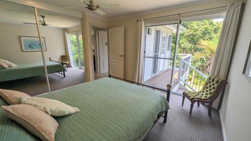 a bedroom with a green bed and a balcony at Rainforest Deluxe Bungalow in Port Macquarie