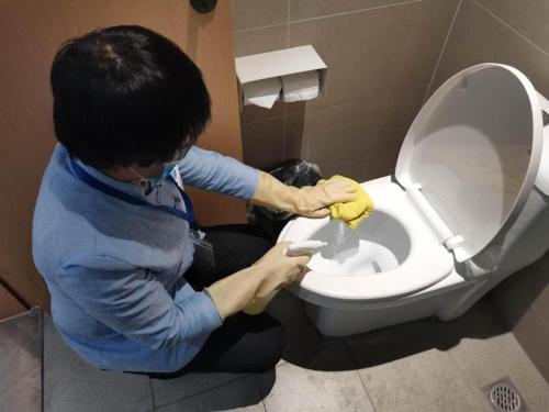 Un hombre está limpiando un baño. en Starway Hotel Hangzhou Yipeng Shopping Center, en Chang-shen-tien