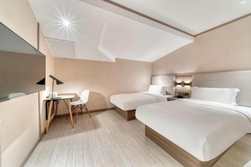 una camera d'albergo con 2 letti e una scrivania di Hanting Hotel Hangzhou East Railway Station Airport Road a Hangzhou