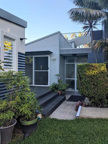 a house with a wooden deck in the yard at Rainforest Cottage in Port Macquarie
