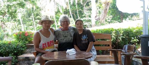 three people sitting on a bench at a table at Venus Resort in Haad Rin
