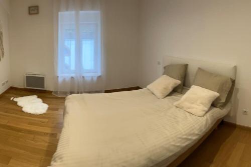 un lit blanc dans une chambre avec une fenêtre dans l'établissement Joli Appartement, à Épinal