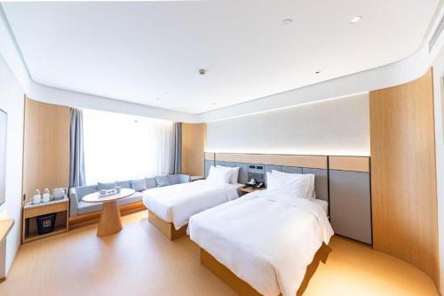 pokój hotelowy z 2 łóżkami i kanapą w obiekcie Ji Hotel Shanghai Daning International w Szanghaju