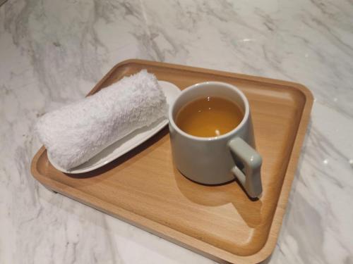 a cup of tea on a wooden tray with a spoon at Lavande Hotel Guangzhou Quzhuang Metro Station in Guangzhou