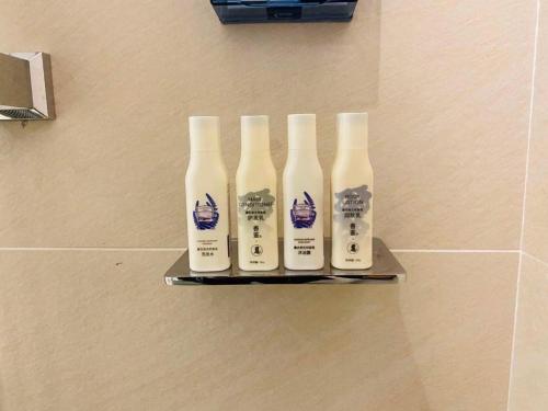 a group of four bottles on a shelf in a bathroom at Lavande Hotel Changchun Gaoxin Jilin University in Changchun