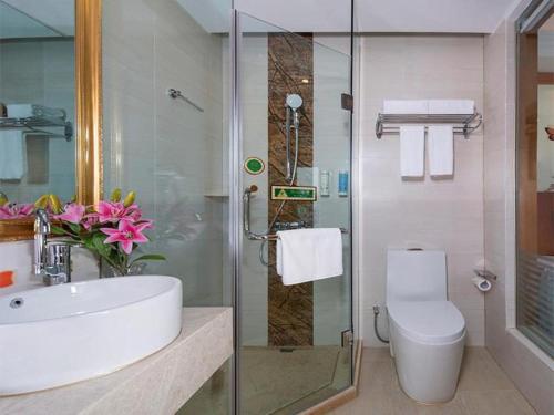 La salle de bains est pourvue d'un lavabo, de toilettes et d'une douche. dans l'établissement Vienna Hotel Zhengzhou Only Henan Movie Town, à Zhongmou