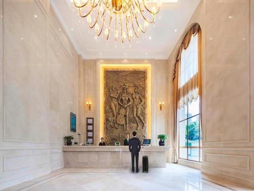 a man in a suit standing in a hallway with a painting at Vienna Hotel Chongqing Jiangjin Shuangfu in Zouma
