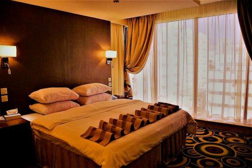 a bedroom with a large bed with a large window at فندق تحسين العزيزية-Tahseen Azizia Hotel in Makkah