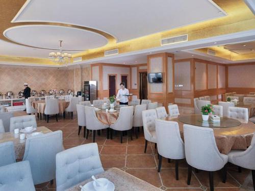 un restaurante con sillas y mesas blancas y una persona en Vienna Hotel Shenzhen Henggang Metro Station en Bingkeng