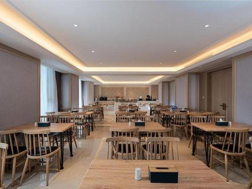 un restaurante con mesas y sillas en una habitación en Vienna Hotel Kunming Dashanghui en Kunming