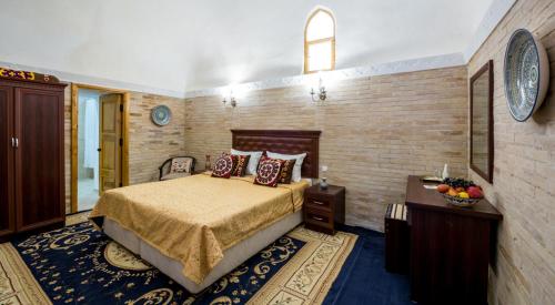 a bedroom with a bed and a brick wall at Orient Star Khiva Hotel- Madrasah Muhammad Aminkhan 1855 in Khiva