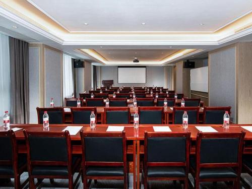a conference room with tables and chairs and a screen at Vienna Hotel Kunming Dashanghui in Kunming