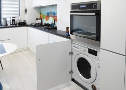 a kitchen with a washing machine and a microwave at Oltenia Studio Happy Residence Craiova in Craiova