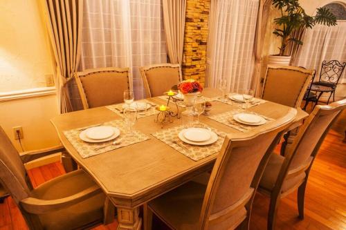 a wooden table with plates and wine glasses on it at 東海岸の美しい海が見える!ラグジュアリーな大豪邸！ in Uruma