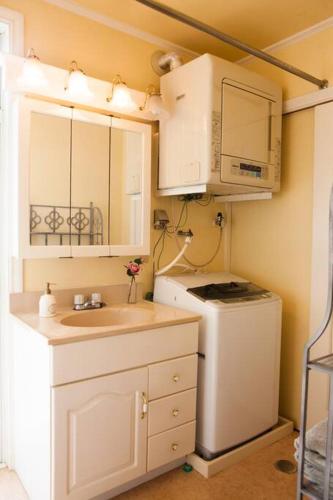a kitchen with a sink and a microwave and a refrigerator at 東海岸の美しい海が見える!ラグジュアリーな大豪邸！ in Uruma