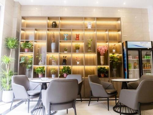 a restaurant with a table and chairs and plants at Shell Hotel Xinzheng Longhu Town Xiang'an Road in Guodian
