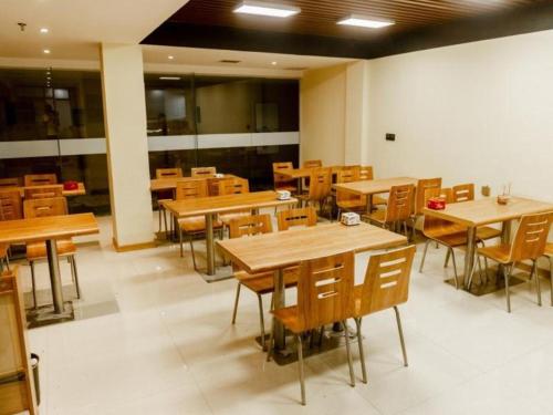 an empty restaurant with wooden tables and chairs at Shell Hotel Xinzheng Longhu Town Xiang'an Road in Guodian
