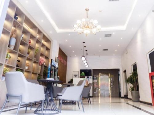 a lobby of a store with white chairs and a chandelier at Shell Hotel Xinzheng Longhu Town Xiang'an Road in Guodian