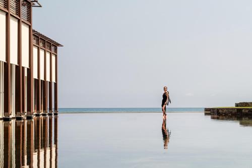 a man standing in the water near the ocean at Amirandes, A Grecotel Resort to Live in Gouves