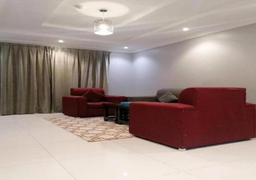 a living room with two red couches and a table at دار ياقوت للشقق المفروشة in Obhor