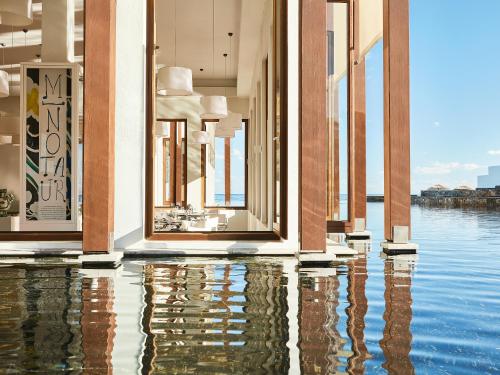 a building with a reflection in the water at Amirandes, A Grecotel Resort to Live in Gouves