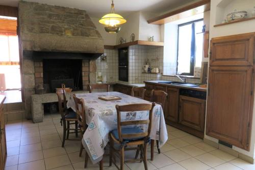une cuisine avec une table et des chaises ainsi qu'une cheminée dans l'établissement Maison bretonne exposée Sud avec jardin à 50m de la baie Ste Anne à TREGASTEL - Réf 44, à Trégastel