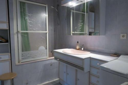 a white bathroom with a sink and a window at Maison bretonne exposée Sud avec jardin à 50m de la baie Ste Anne à TREGASTEL - Réf 44 in Trégastel