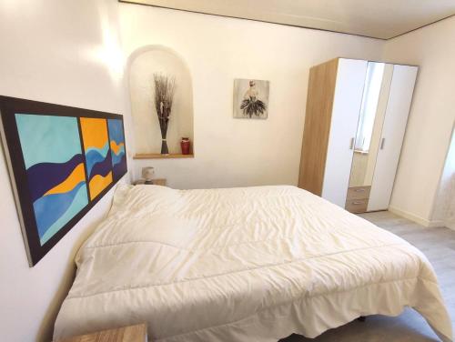 a bedroom with a white bed with a painting on the wall at Appartement au centre de TREBEURDEN et à 500m de la plage - Ref 665 in Trébeurden