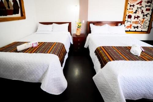 una camera d'albergo con due letti con lenzuola bianche di Tourist house 1 a Otavalo