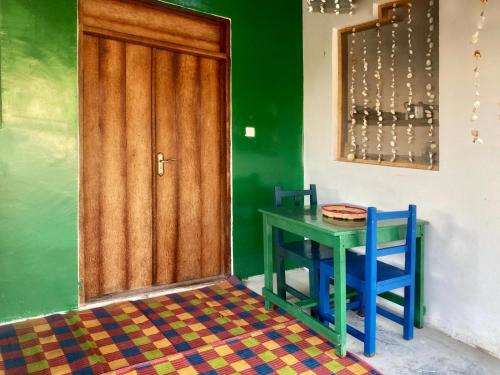 uma mesa e duas cadeiras num quarto com uma porta em Zanzibat bungalow em Kendwa
