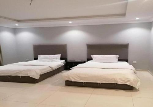 1 dormitorio con 2 camas con sábanas blancas en دار ياقوت للشقق المفروشة en Obhor