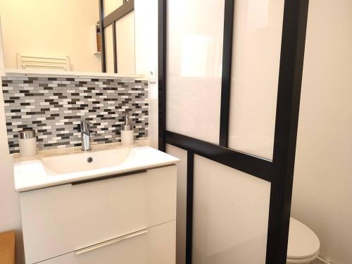 La salle de bains est pourvue d'un lavabo et d'un miroir. dans l'établissement Appartement avec WIFI, terrasse, jardin à TREBEURDEN Réf - 678, à Trébeurden