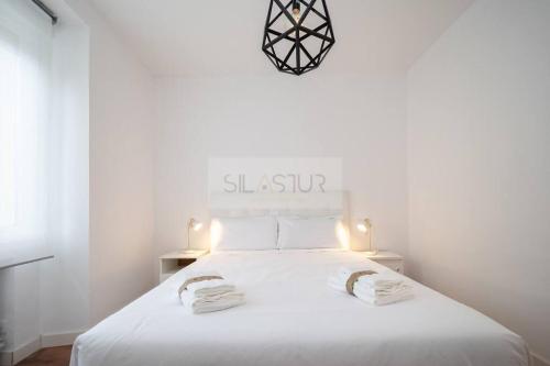 a bedroom with a white bed with two towels on it at Vive Oviedo II Apartamento in Oviedo