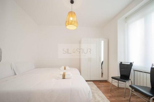 1 dormitorio blanco con 1 cama y 2 sillas en Vive Oviedo II Apartamento, en Oviedo