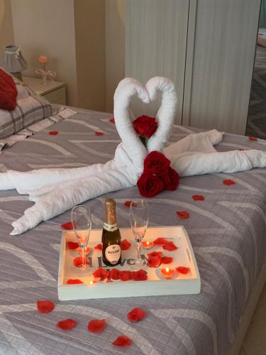 a bed with a tray with a bottle of champagne and roses at B&B La Penisola in Gragnano